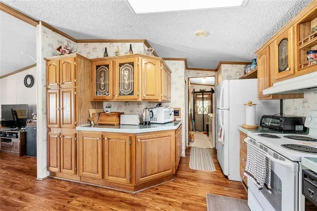a kitchen with stainless steel appliances granite countertop a refrigerator a stove and a sink with wooden floor