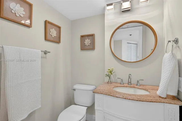 a bathroom with a granite countertop toilet a sink and a mirror