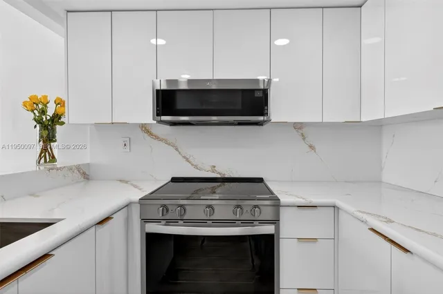a kitchen with stainless steel appliances a stove a white cabinets and a sink