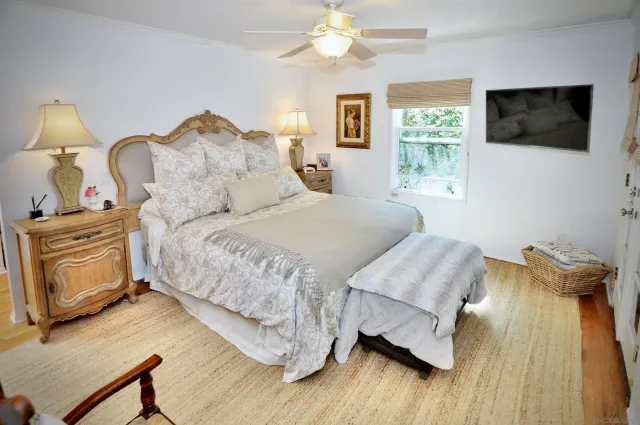 a bedroom with a bed a flat screen tv and a chandelier