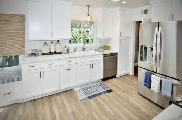 a kitchen with granite countertop a refrigerator sink and white cabinets