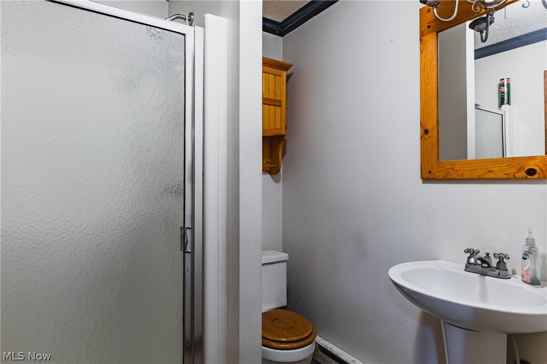 279 Spence Road Belpre, OH 45714 - Photo 28 of 40 Bathroom featuring toilet, crown molding, a shower with shower door, sink, and a textured ceiling