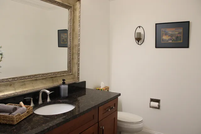 a bathroom with a granite countertop toilet sink and mirror