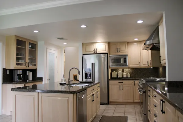 a kitchen with stainless steel appliances granite countertop a sink stove refrigerator and cabinets