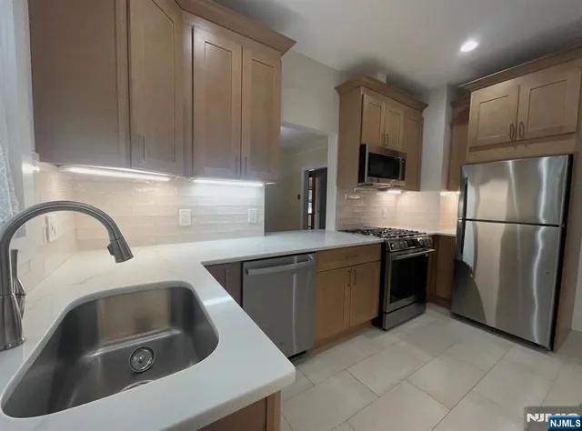 a kitchen with stainless steel appliances granite countertop a sink a stove a refrigerator a washer and dryer