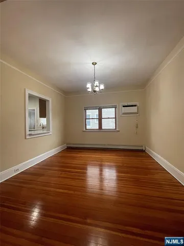 a view of an empty room with window and wooden floor