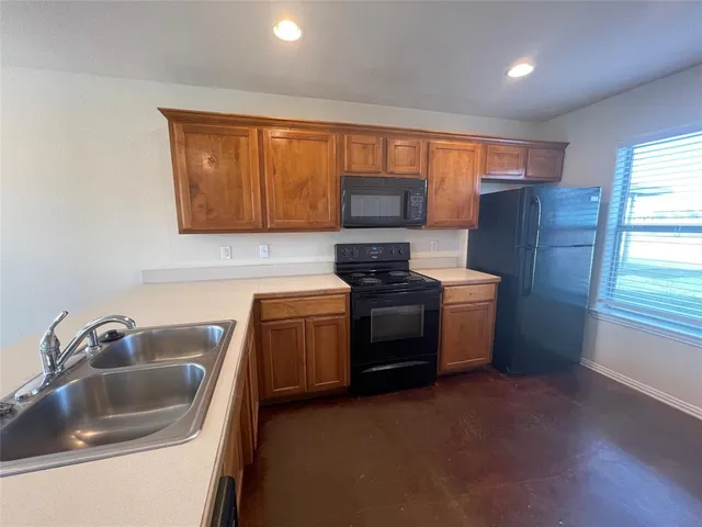 a view of kitchen with stainless steel appliances wooden floor and chair