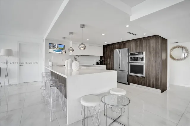 a living room with stainless steel appliances kitchen island granite countertop a refrigerator a sink a dining table and chairs with wooden floor