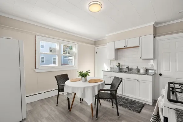 a kitchen with granite countertop a dining table chairs and white cabinets
