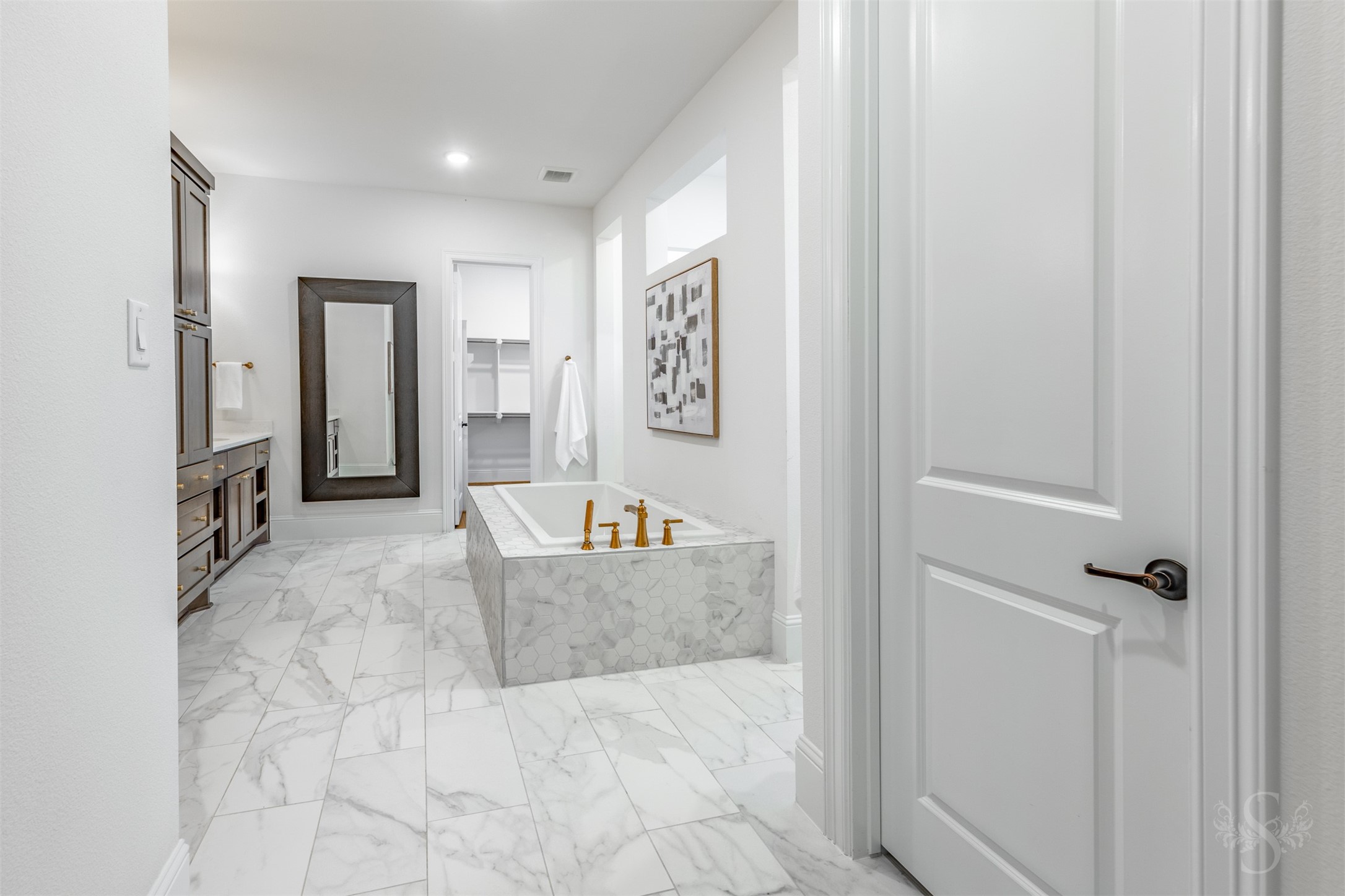 27919 Indigo Ridge Drive Fulshear, TX 77441 - Photo 26 of 50 This spa-inspired primary bath features a stunning marble-look tile floor, a deep soaking tub with designer hex tile surround, and elegant gold fixtures that bring a touch of refinement. A spacious layout leads directly into the walk-in closet, creating a seamless and elevated daily experience.