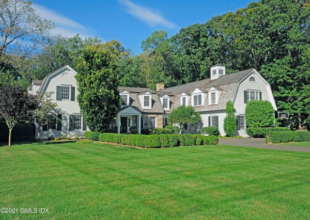 a view of a house next to a big yard and large trees