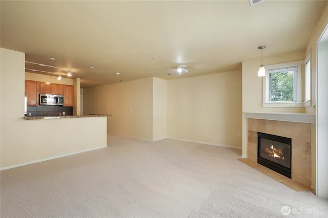 a view of empty room with kitchen and fireplace