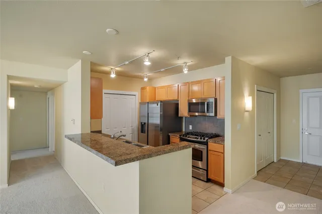 a kitchen with stainless steel appliances kitchen island granite countertop a refrigerator and a stove top oven