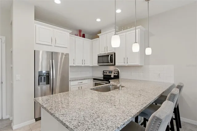a kitchen with stainless steel appliances granite countertop a sink a stove a refrigerator and a refrigerator