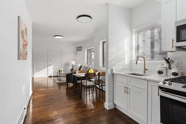 a kitchen with stainless steel appliances granite countertop a stove top oven a sink a dining table and chairs with wooden floor