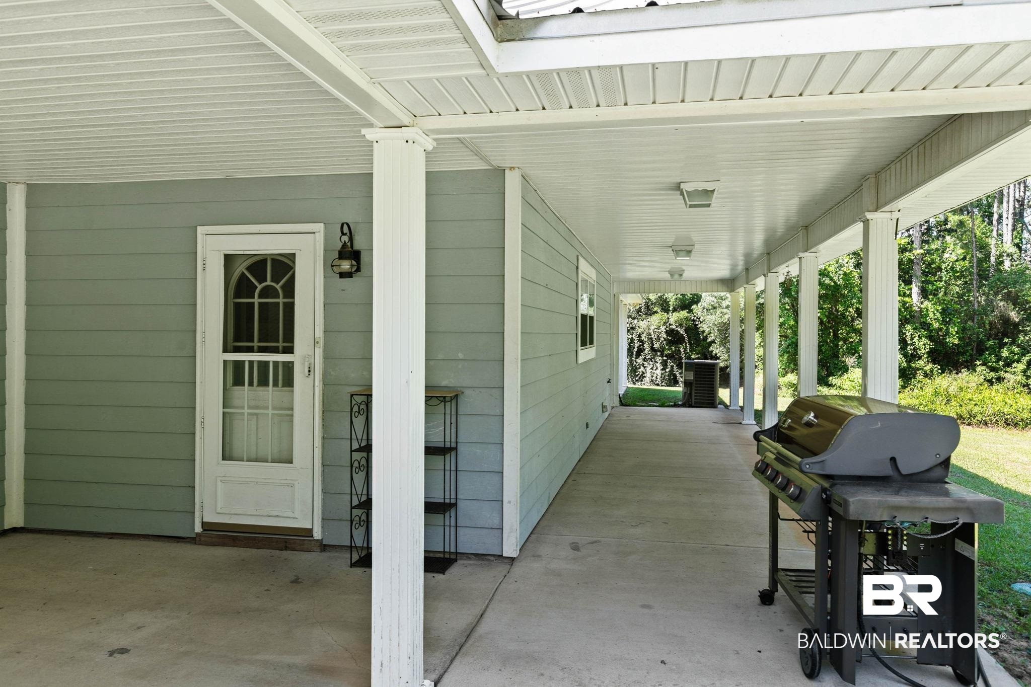 20219 Greek Cemetery Road Robertsdale, AL 36567 - Photo 32 of 41 Expansive covered porch featuring a concrete slab, white columns, and a beadboard ceiling with integrated lighting