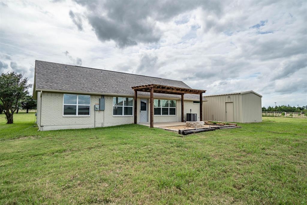 13132 Highway 78 Blue Ridge, TX 75424 - Photo 22 of 35 Rear exterior featuring a covered patio with a wood pergola, brick facade, shingle roof, and a separate utility building