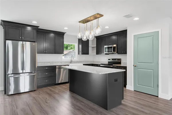 a large kitchen with stainless steel appliances kitchen island granite countertop a sink and cabinets