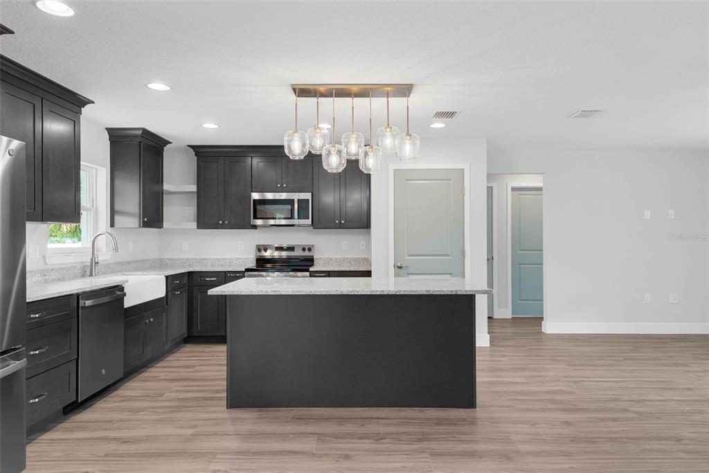 261 South Main Street Bunnell, FL 32110 - Photo 12 of 56 a large kitchen with stainless steel appliances kitchen island granite countertop a sink and cabinets