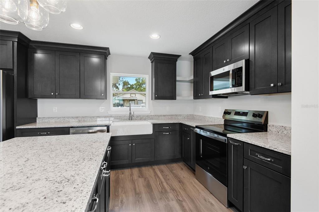 261 South Main Street Bunnell, FL 32110 - Photo 18 of 56 a kitchen with stainless steel appliances granite countertop wooden cabinets a stove top oven a sink and dishwasher