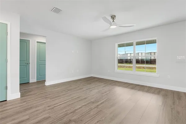 an empty room with wooden floor and windows