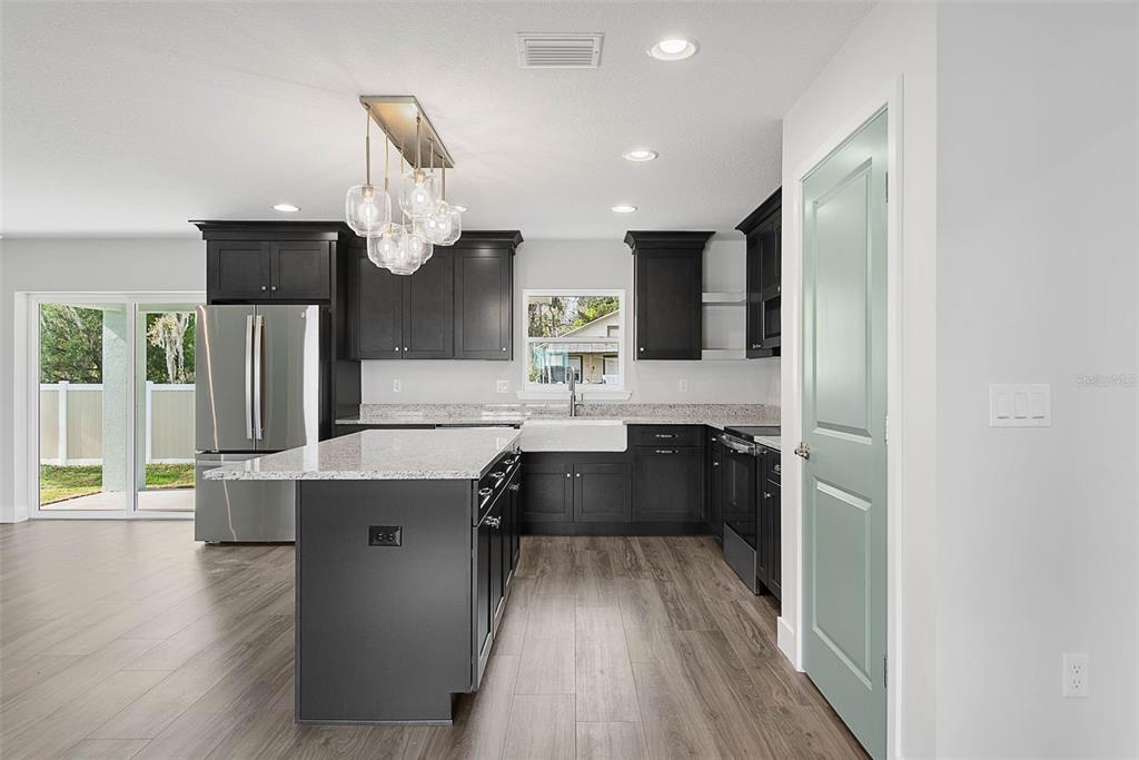 261 South Main Street Bunnell, FL 32110 - Photo 10 of 56 a kitchen with stainless steel appliances granite countertop a refrigerator a sink dishwasher a stove and a dining table with wooden floor