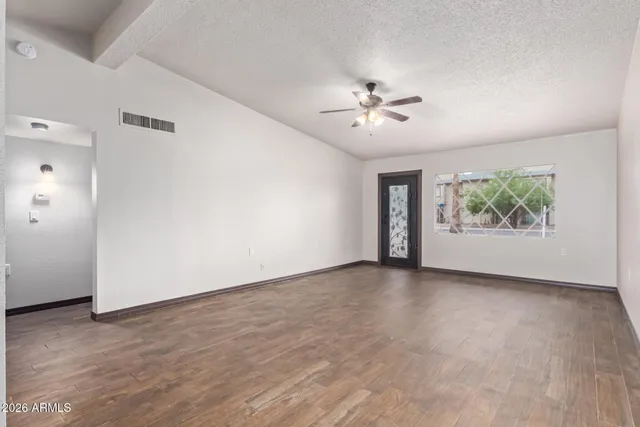 a view of an empty room with window and wooden floor