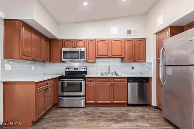 a kitchen with stainless steel appliances granite countertop a stove top oven a refrigerator and a sink with granite countertops