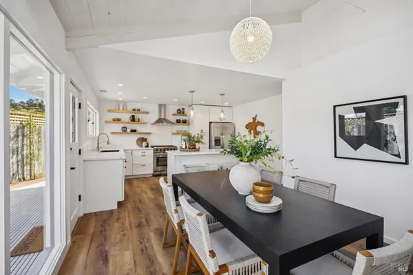 a large white kitchen with stainless steel appliances granite countertop a sink a stove a refrigerator and island with wooden floor