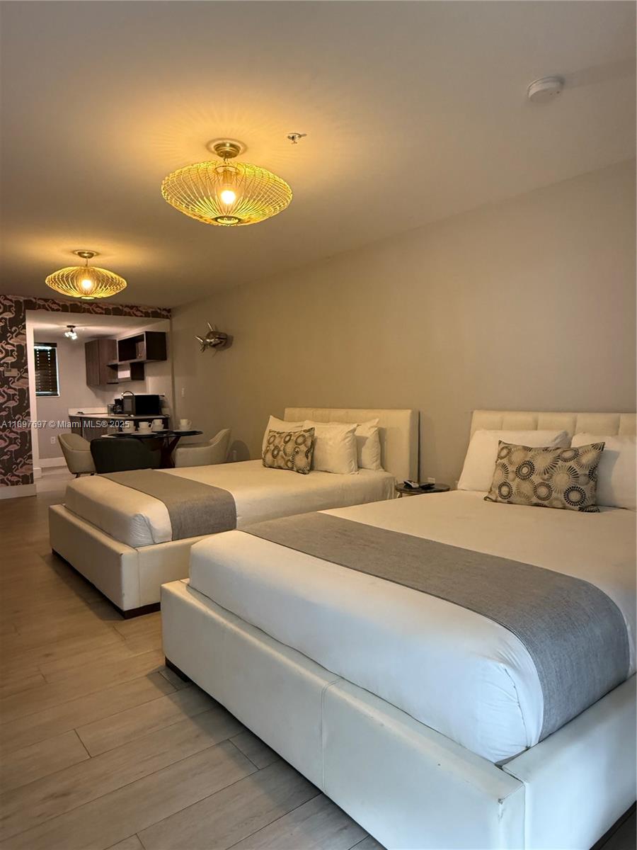6755 Harding Avenue, Unit 2 Miami Beach, FL 33141 - Photo 9 of 10 a spacious bedroom with two beds and a chandelier