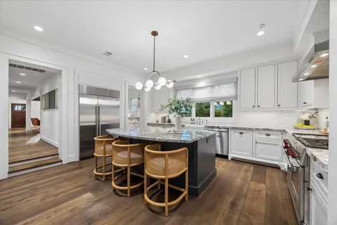 a kitchen with stainless steel appliances granite countertop a kitchen island hardwood floor sink stove dining table and chairs