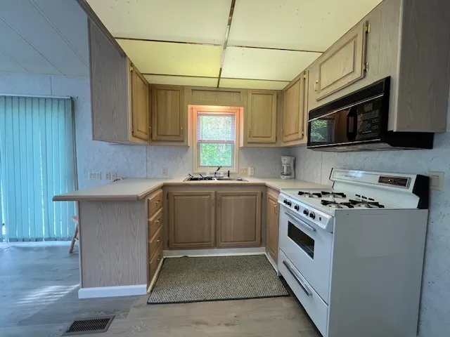a kitchen with stainless steel appliances granite countertop a stove a sink and a microwave