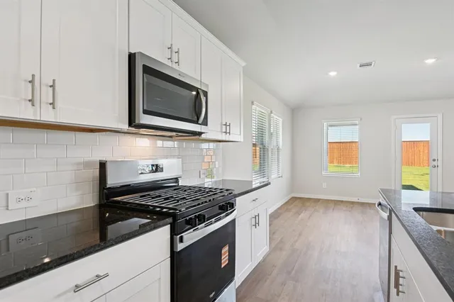 a kitchen with stainless steel appliances kitchen island granite countertop a stove a sink and a microwave