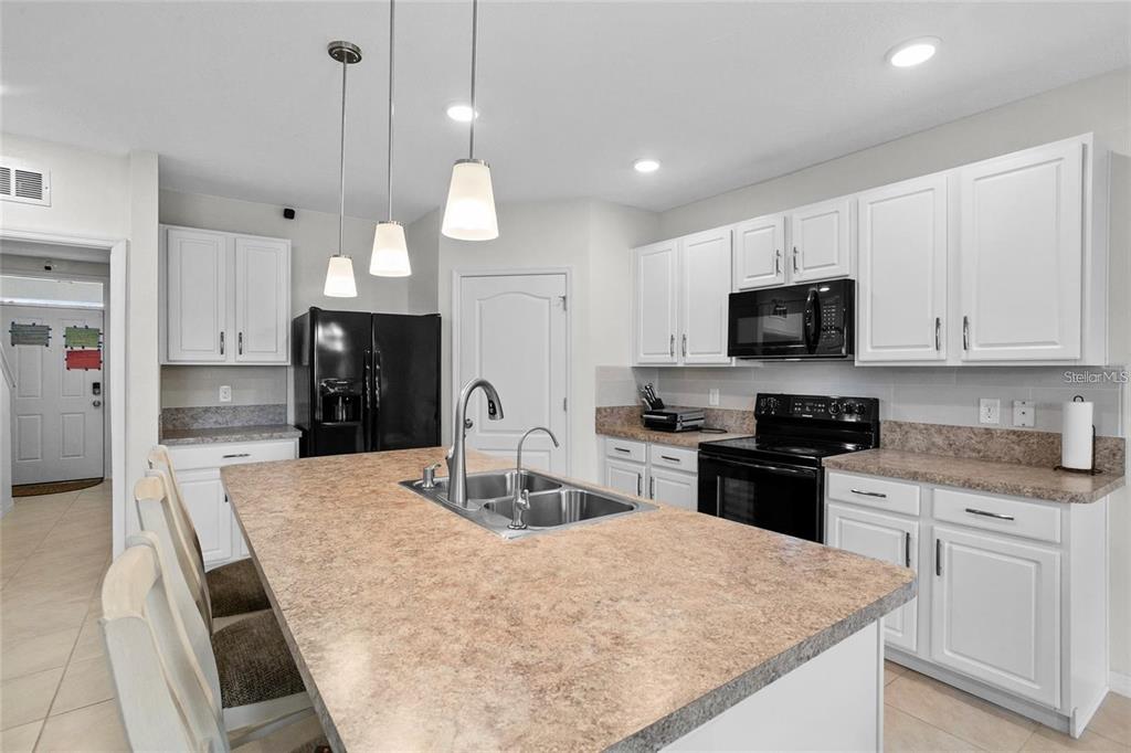 1872 Rustic Falls Drive Kissimmee, FL 34744 - Photo 11 of 30 a kitchen with stainless steel appliances kitchen island granite countertop a refrigerator a stove top oven a sink a stove and a refrigerator