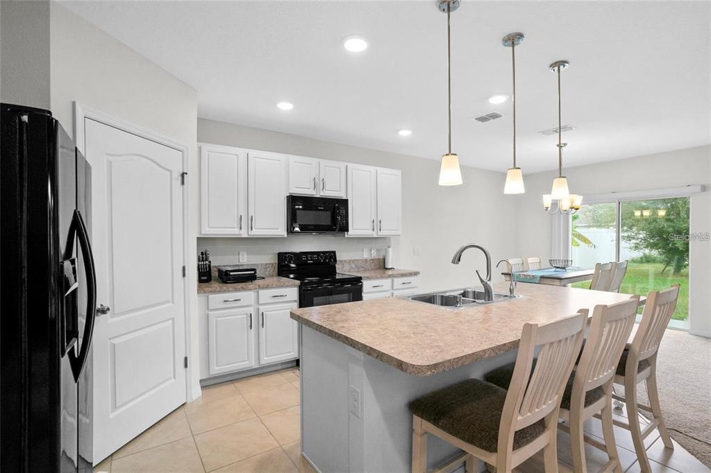 1872 Rustic Falls Drive Kissimmee, FL 34744 - Photo 12 of 30 a kitchen with stainless steel appliances kitchen island granite countertop a stove a sink a refrigerator a center island with a dining table and chairs