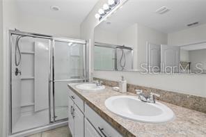 1872 Rustic Falls Drive Kissimmee, FL 34744 - Photo 24 of 30 a bathroom with a granite countertop sink a mirror and a shower