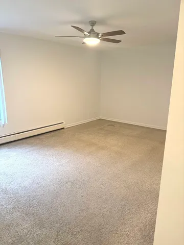 an empty room with a ceiling fan and carpet