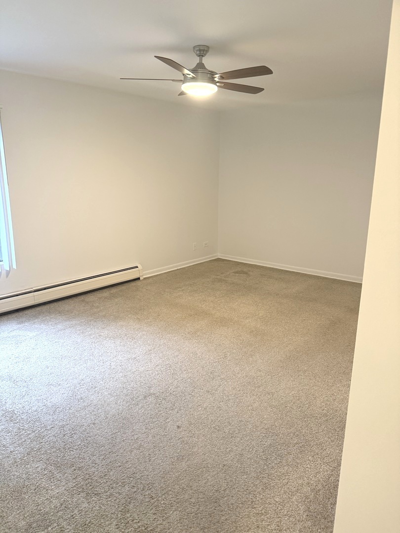 1149 Miller Lane, Unit 212 Buffalo Grove, IL 60089 - Photo 12 of 20 an empty room with a ceiling fan and carpet