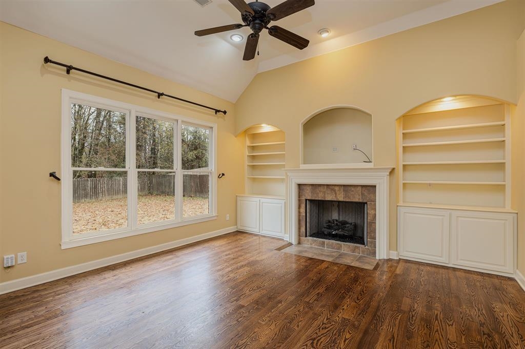 5380 Scarlet Ridge Drive Arlington, TN 38002 - Photo 12 of 35 Vaulted living space featuring rich wood-finish flooring, a central fireplace with a tile surround and mantel, and built-in shelving with lower cabinetry