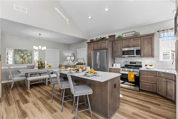 a kitchen with stainless steel appliances granite countertop a stove top oven a refrigerator a sink dishwasher and white cabinets with wooden floor