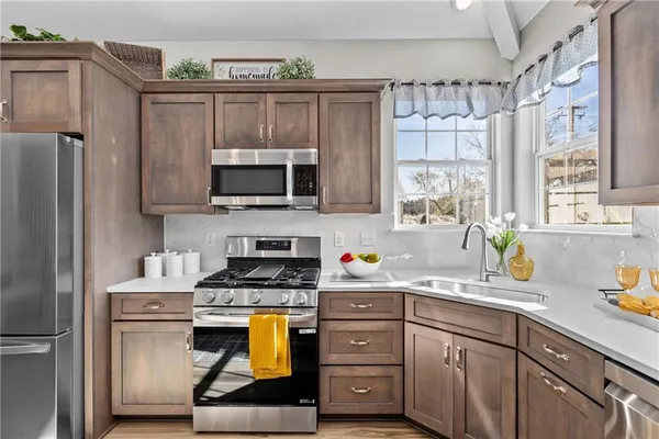 a kitchen with stainless steel appliances a stove a sink cabinets and a window