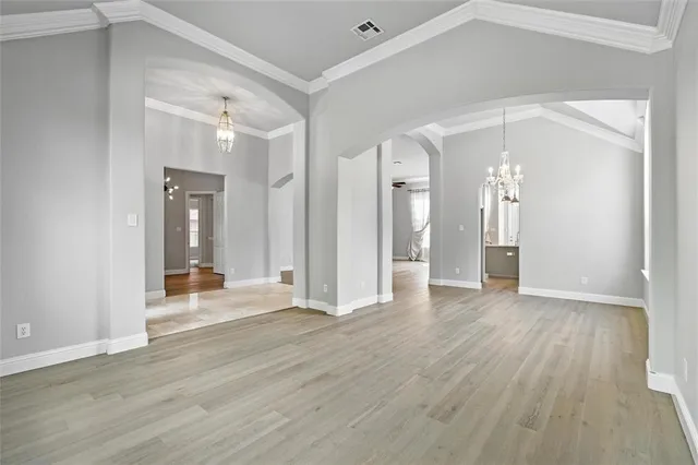 a view of an empty room with chandelier fan and wooden floor