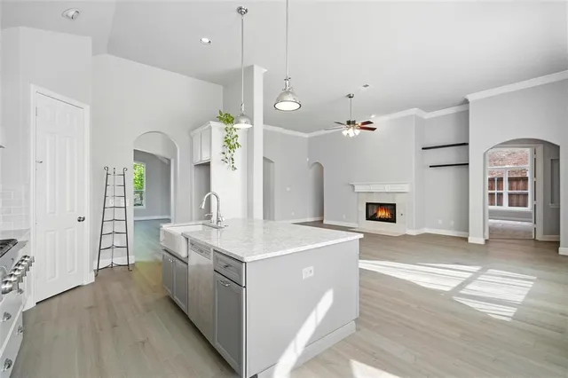 a large white kitchen with a stove a sink dishwasher and a refrigerator with wooden floor