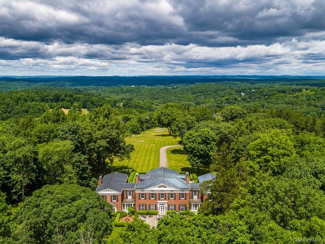 aerial view of a house with a big yard and large trees