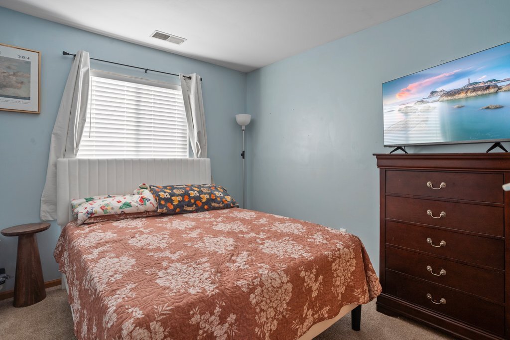 232 Stamford Lane Romeoville, IL 60446 - Photo 23 of 48 a bedroom with a bed and a flat tv screen on dresser