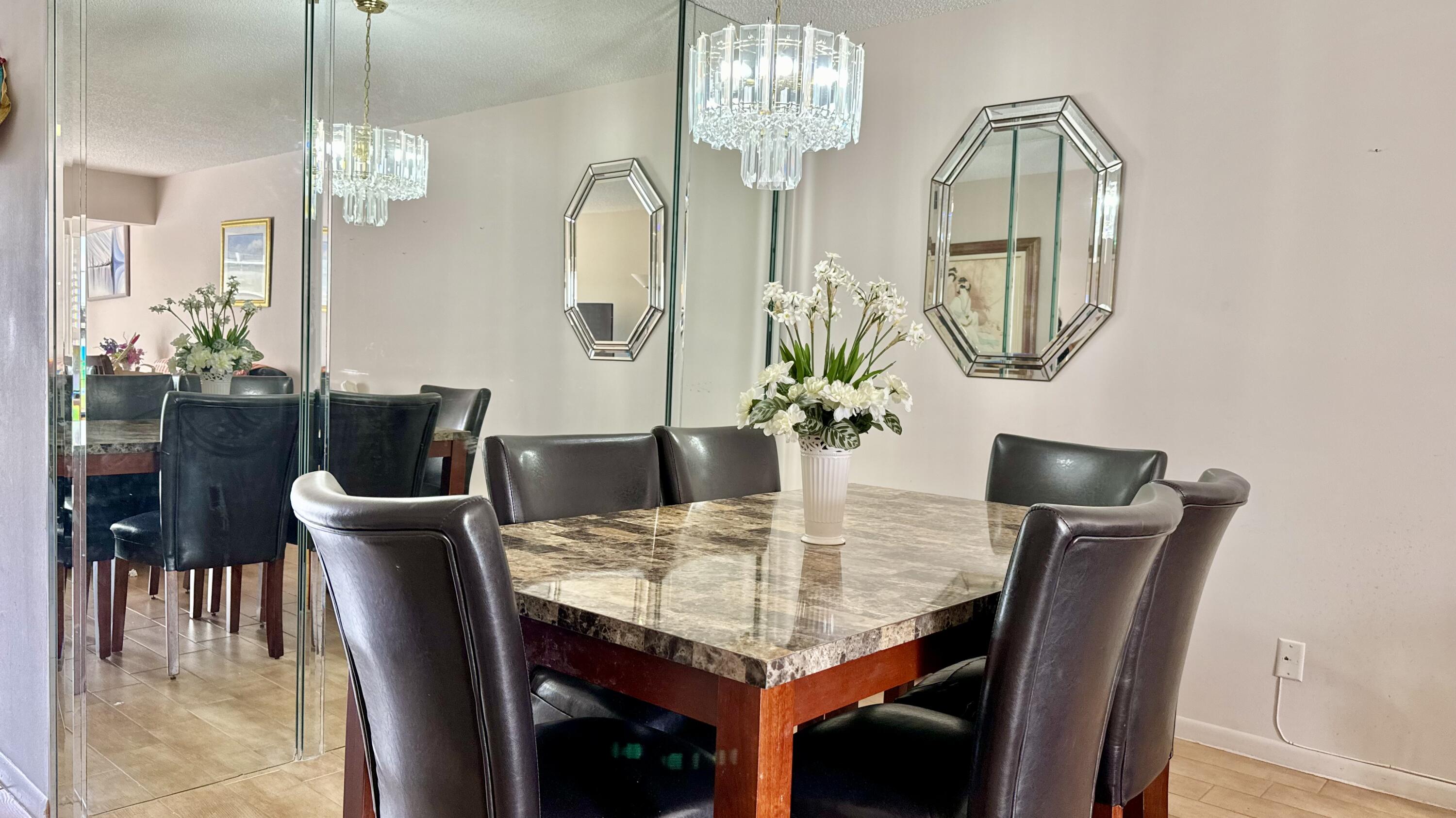 1551 Northwest 20th Avenue, Unit 102 Delray Beach, FL 33445 - Photo 13 of 18 a view of a dining room with furniture and chandelier