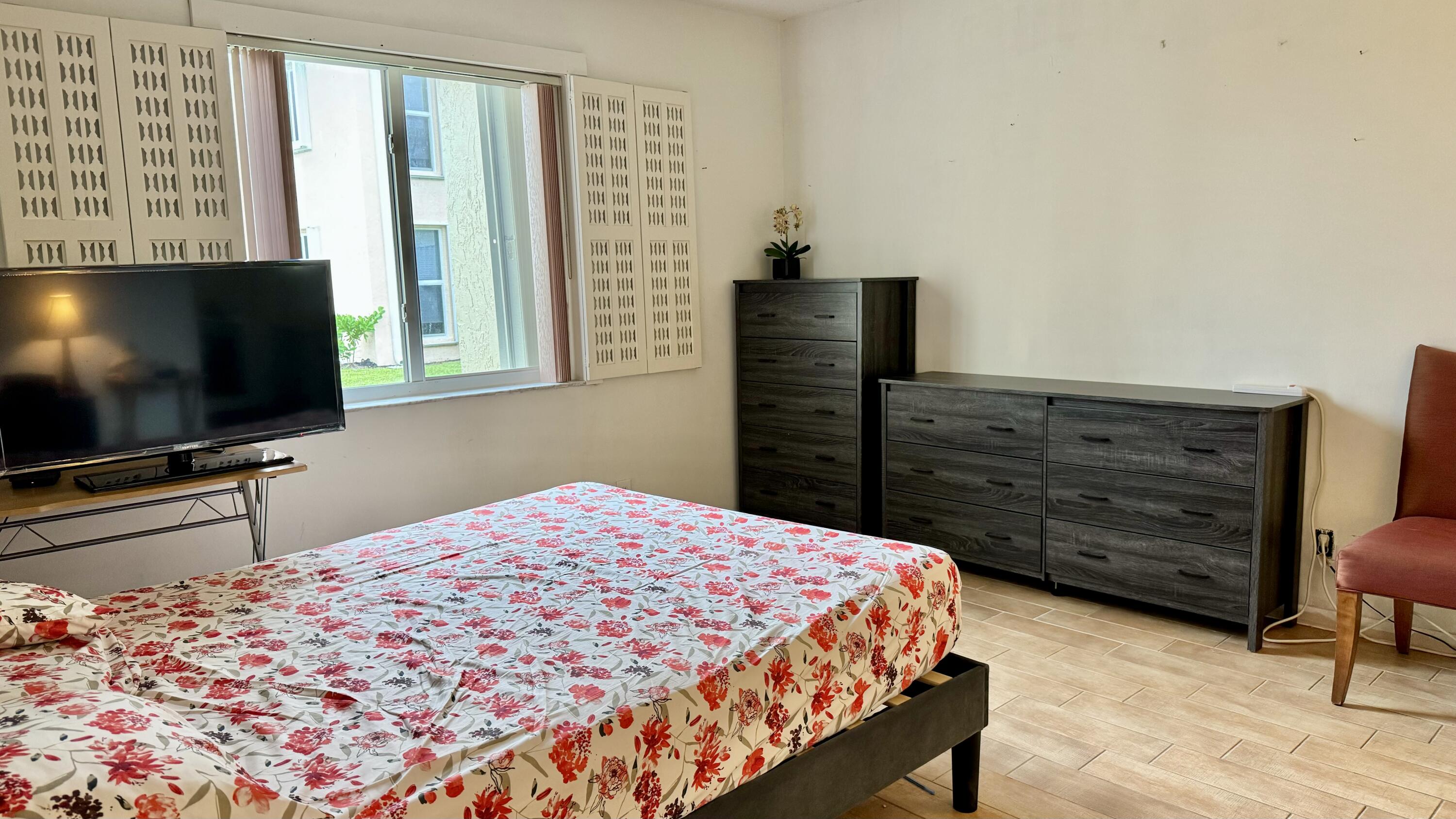 1551 Northwest 20th Avenue, Unit 102 Delray Beach, FL 33445 - Photo 15 of 18 a bedroom with a bed and a flat screen tv