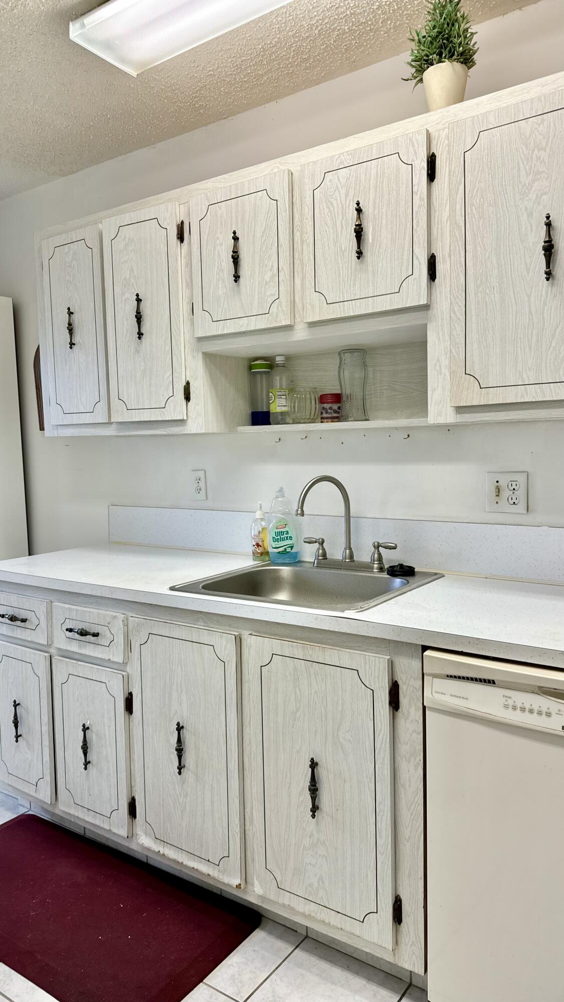 1551 Northwest 20th Avenue, Unit 102 Delray Beach, FL 33445 - Photo 5 of 18 a kitchen with white cabinets and sink