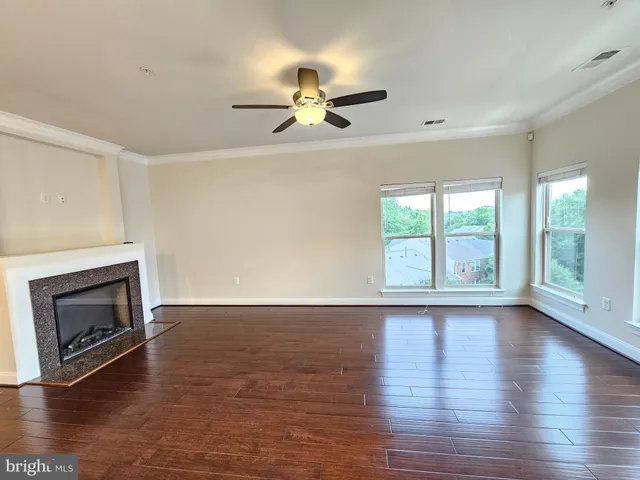 a view of an empty room with wooden floor fireplace and a window