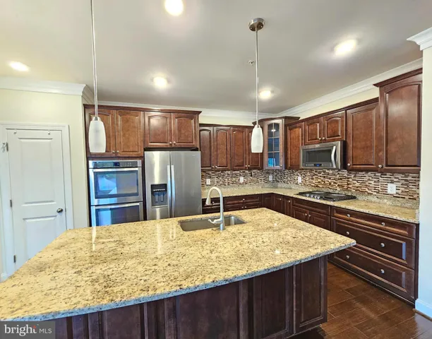 a kitchen with stainless steel appliances granite countertop a sink refrigerator and cabinets